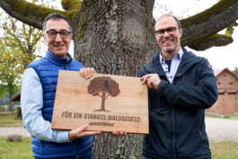 Cem Ozdemir und Martin Kaiser (Greenpeace) halten ein Schild: Für ein starkes Waldgesetz!