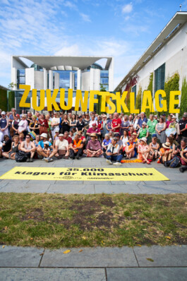 Von dem Kanzleramt stehen viele Menschen und die Buchstaben "Zukunftsklage"